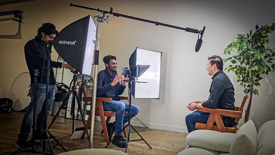 The DK Visualsx team: Dominic and a crew member filming an interview with camera, lighting and sound equipment